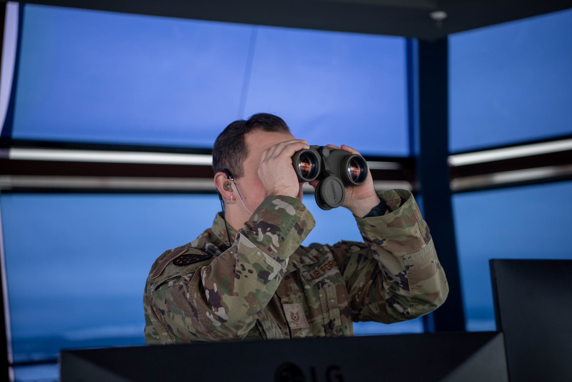 A service member looks through binoculars.