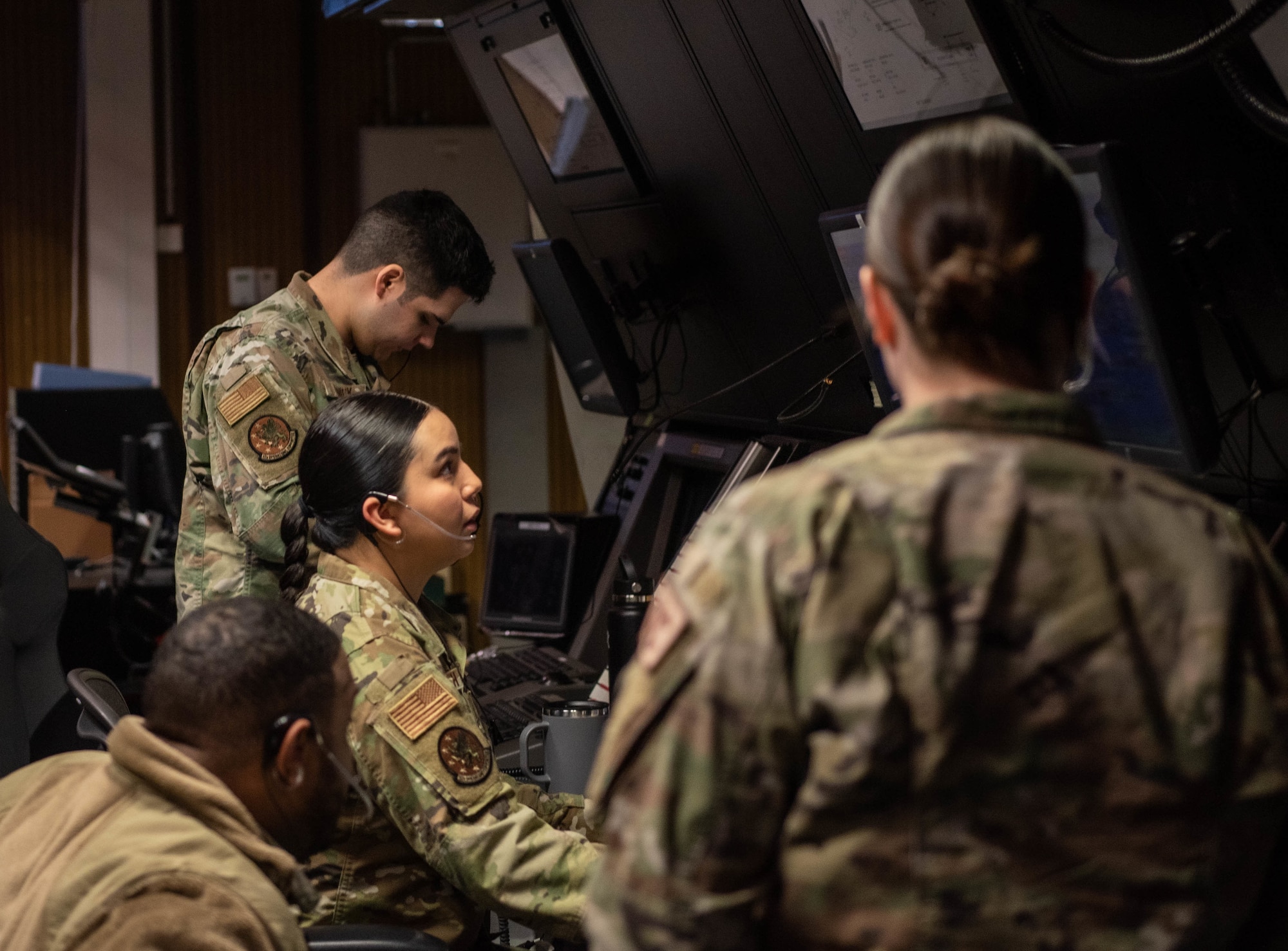 Service members gather at a screen.