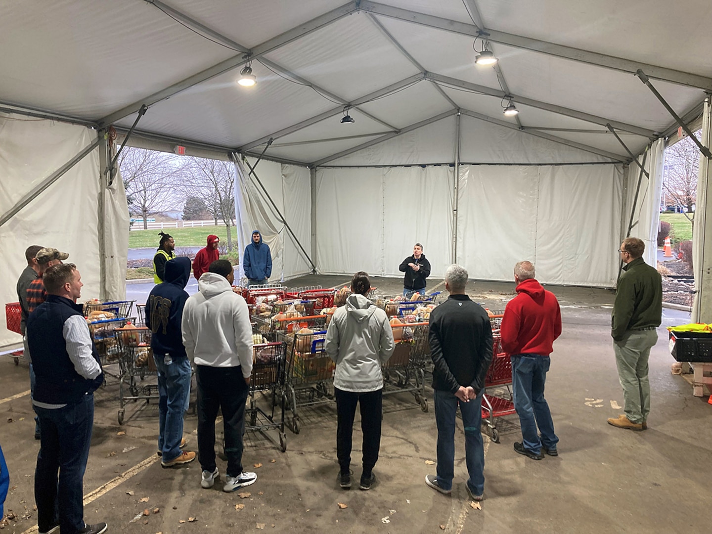 A group of people in casual clothing standing in an outside distribution tent.