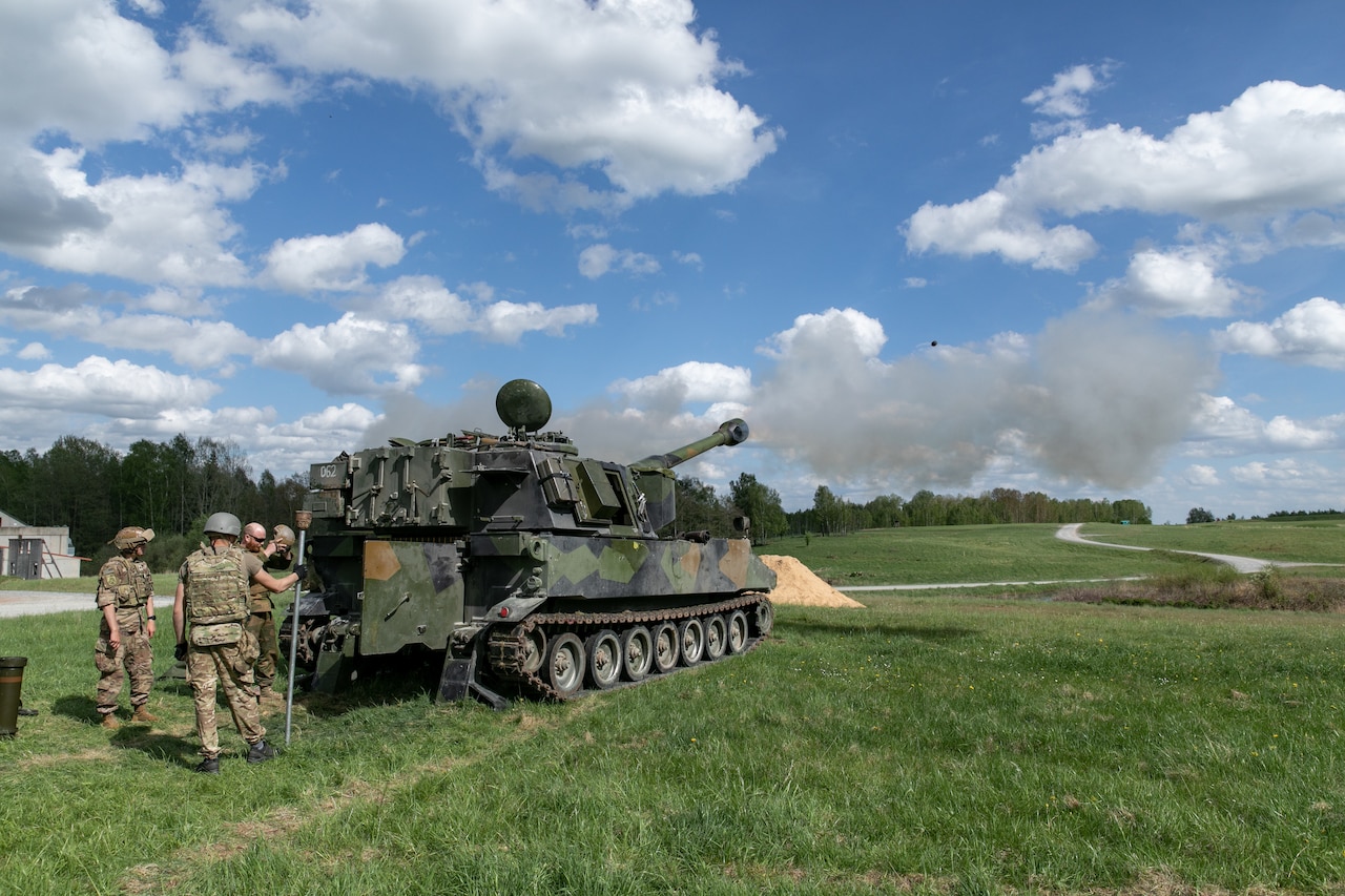 A large combat vehicle fires a round.