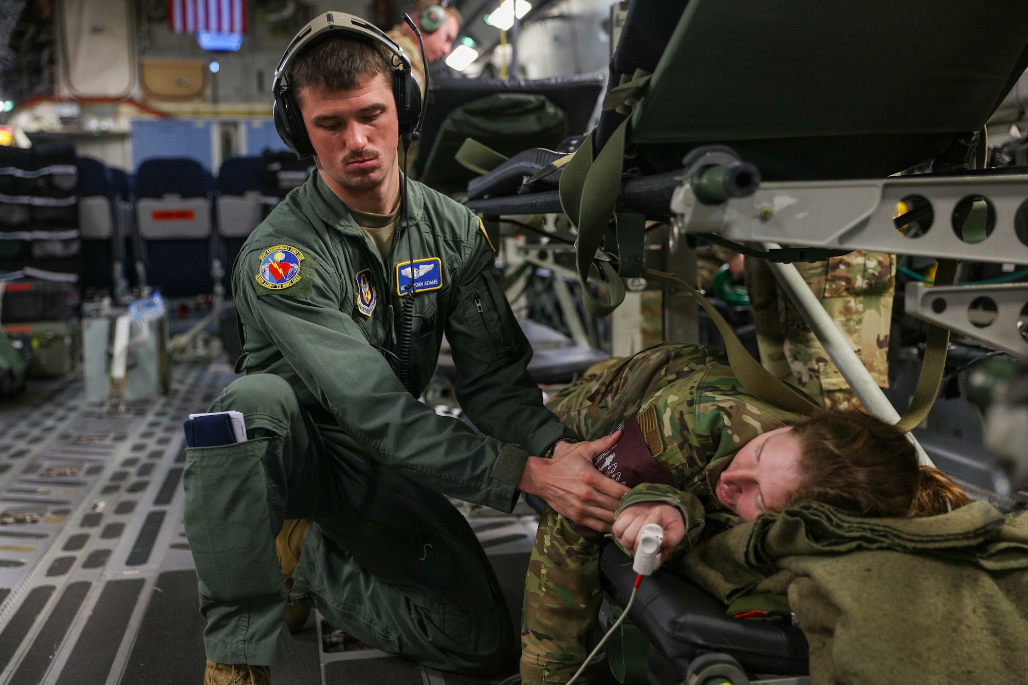 Senior Airman Brandan Adams, 445th Aeromedical Evacuation Squadron AE medical technician, checks the vitals on a “patient” played by Lt. Col. Jessica Brantner, 445th AES flight nurse, during a medical training scenario onboard a C-17 Globemaster III Jan. 20, 2023. The AE flight was part of the 445th Airlift Wing training event held in San Diego, California, Jan. 18-23. Over 150 Reservists from the 445th Airlift Wing, to include 445th Aeromedical Evacuation Squadron, 445th Aerospace Medicine Squadron, 445th Operations Support Squadron, 445th Maintenance Group, 445th Aircraft Maintenance Squadron, 445th Maintenance Squadron, 87th Aerial Port Squadron and 89th Airlift Wing provided support or participated in the training event that included water survival, AES training flights and urban survival, evasion, resistance and escape.