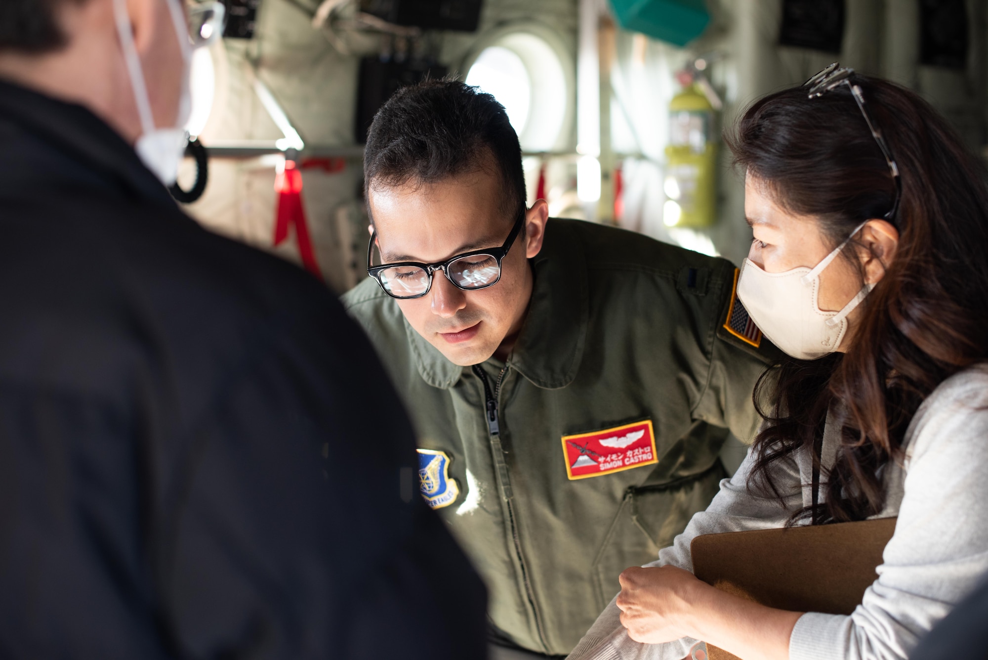 A Japanese woman whispers into the ear of a larger American man.