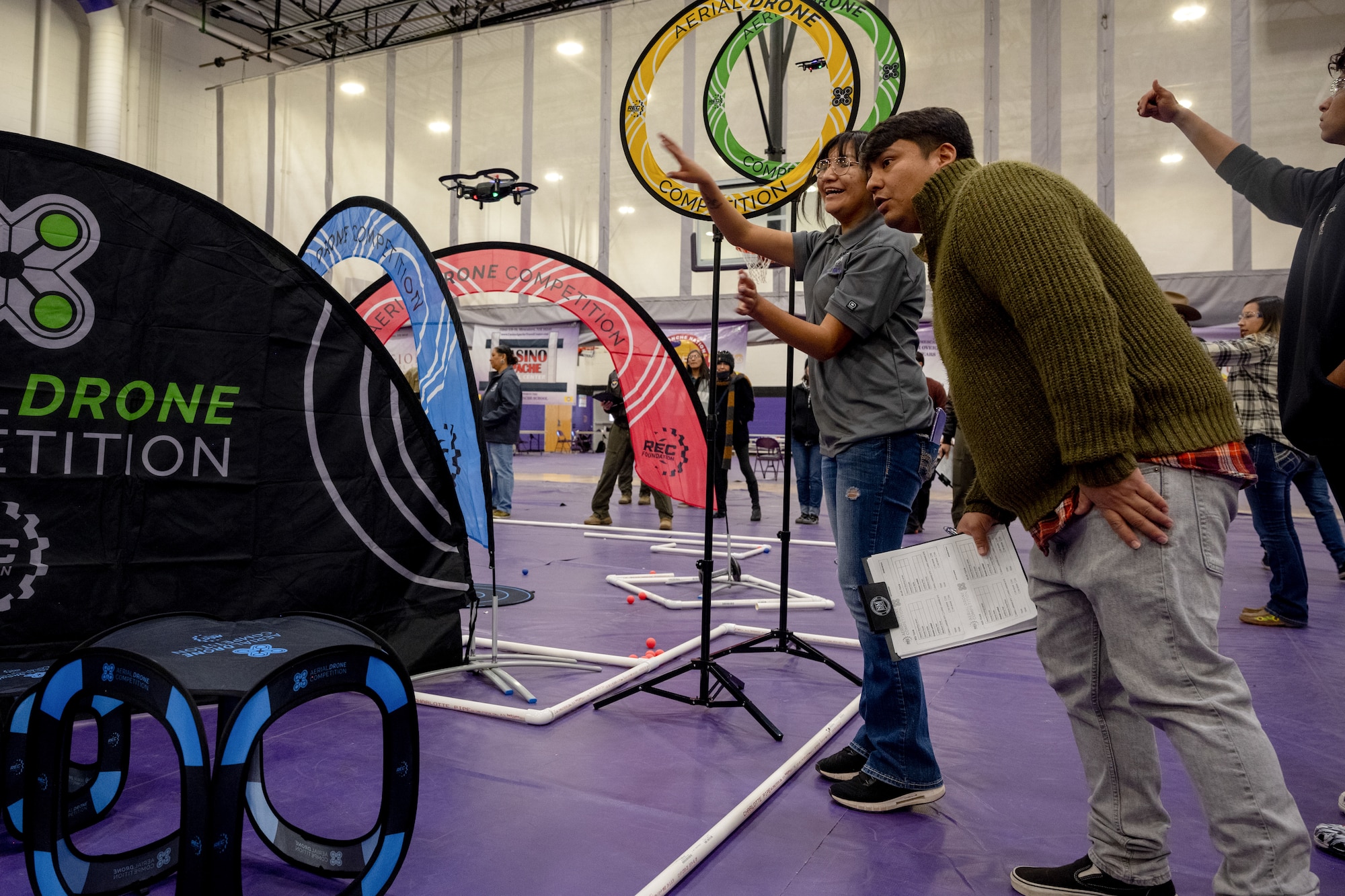 U.S. Air Force Master Sgt. Enrique Towry, right, 49th Operations Group standardization and evaluation superintendent, watches closely during the first Aerial Drone Competition at Mescalero Apache High School, Jan. 21, 2023. The team of pilots and sensor operators from the 29th Attack Squadron were able to attend a training session where they learned the rules of the competition. (U.S. Air Force photo by Senior Airman Antonio Salfran)