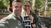 U.S. Air Force Maj. Lauren Olme, 77th Weapons Squadron assistant director of operations, and her husband, Maj. Mark Olme, 7th Operations Support Squadron bomb wing weapons officer, pose with an ultrasound photo of their child at Dyess Air Force Base, Texas, Jan. 24, 2023. Lauren, who is currently pregnant, can continue flying after recently getting approved under the Air Force’s new guidance which allows female aircrew members to voluntarily request to fly during pregnancy. No waiver is required to fly in the second trimester with an uncomplicated pregnancy in a non-ejection seat aircraft if all flight safety criteria are met. All pregnant aircrew members are also authorized to apply for a waiver regardless of trimester, aircraft or flight profile. (Courtesy photo)
