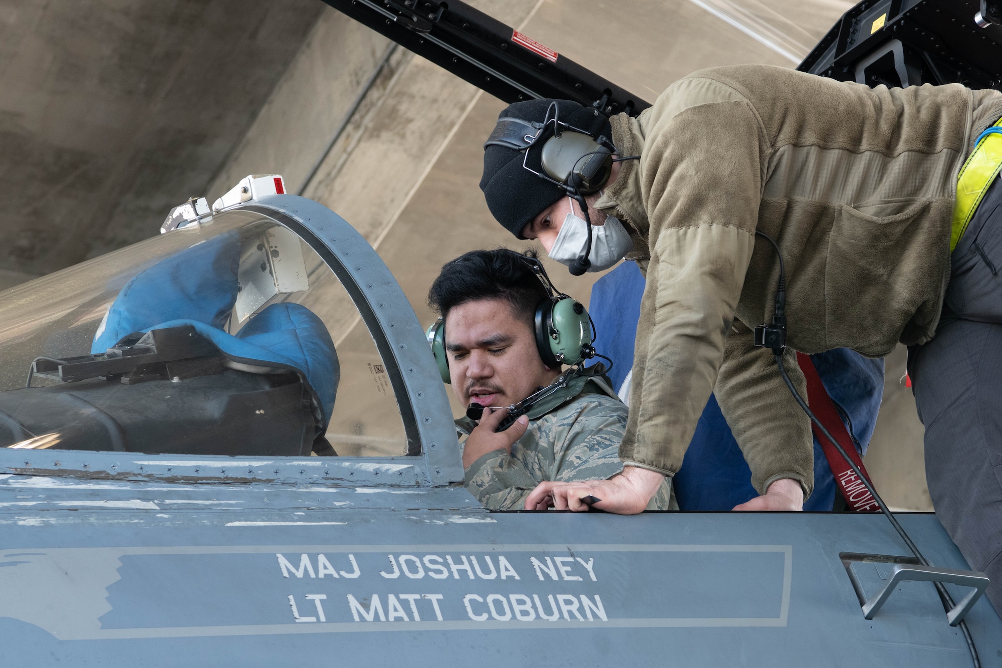Airmen perform maintenance in an aircraft cockpit.