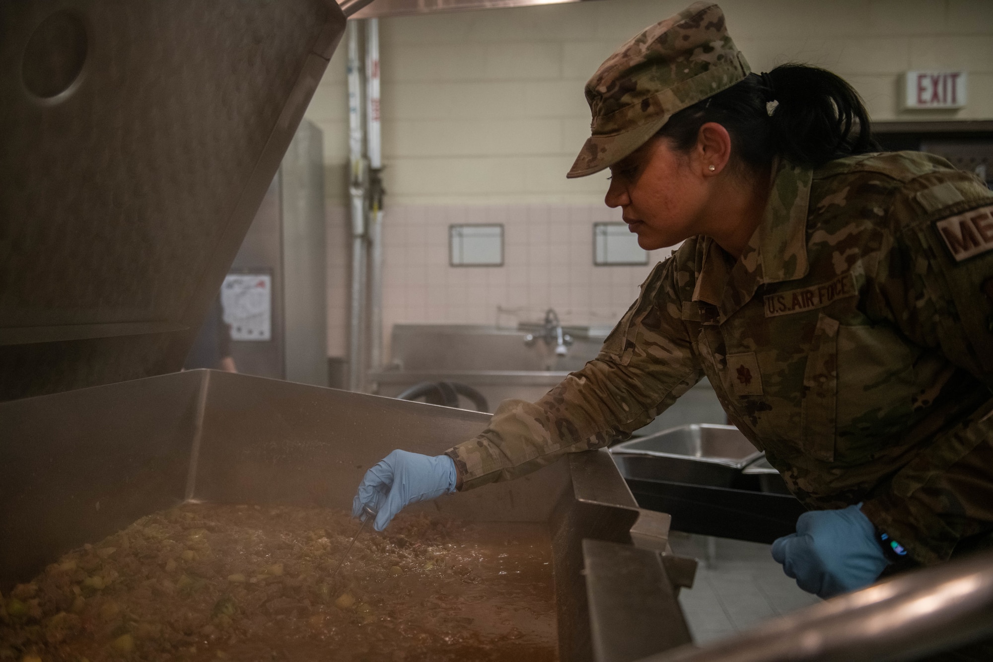 Dr. (Maj.) Tanviben Patel, 8th Operational Medical Readiness Squadron public health flight commander, inspects food at the dining facility on Kunsan Air Base, Republic of Korea, Jan. 24, 2023. Public health officers manage programs that focus on the following: food safety and public facility sanitation, disease surveillance and prevention, force health management and medical readiness, vector surveillance and entomology, and occupational and environmental health. (U.S. Air Force photo illustration by 1st Lt. Cameron Silver)