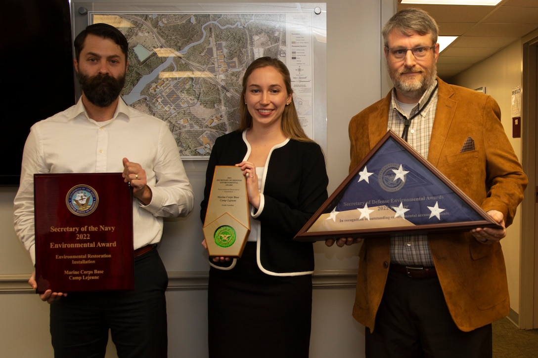 Thomas Richard, left, installation restoration program manager, Laura Spung, center, installation restoration program assistant, and William Hagen Ratliff, right, underground storage tank program manager, all with the Environmental Quality Branch, pose for a photo after receiving the 2022 Secretary of Defense and Secretary of the Navy Environmental Awards for Environmental Restoration after an awards presentation on Marine Corps Base Camp Lejeune, North Carolina, Dec. 21, 2022. The SECDEF and SECNAV Environmental Awards recognize installations, teams, and individuals for their accomplishments in innovative and cost-effective environmental management strategies supporting mission readiness.