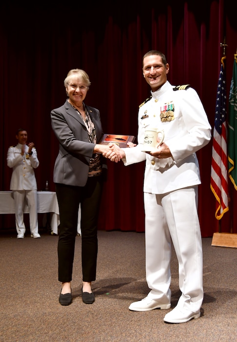 Commander Michael Felber, commanding officer, HT-28, presents Captain Oslund, USN Ret. with a plaque and squadron mug during the winging ceremony on Oct. 21, 2022.