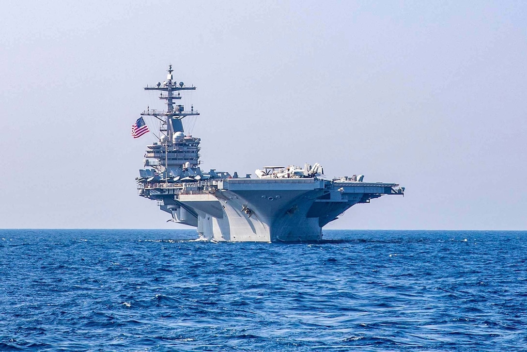 A Navy aircraft carrier is shown sailing the open sea.