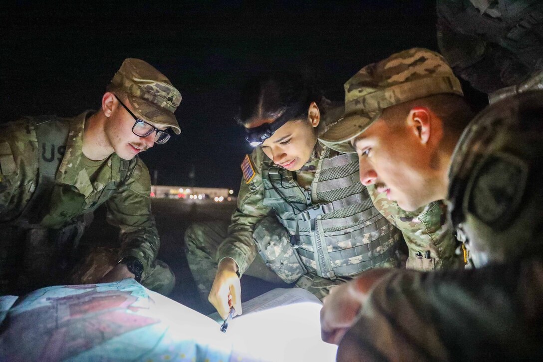 Three service members review a map at night.