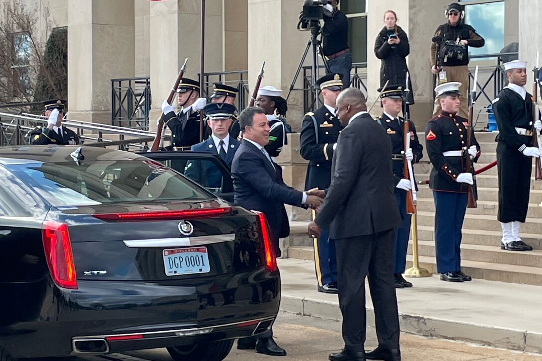 Two men shake hands at steps of Pentagon.
