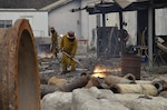 Men cut weapons with torch.