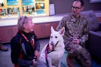 Man in military uniform talks to a dog handler and her dog