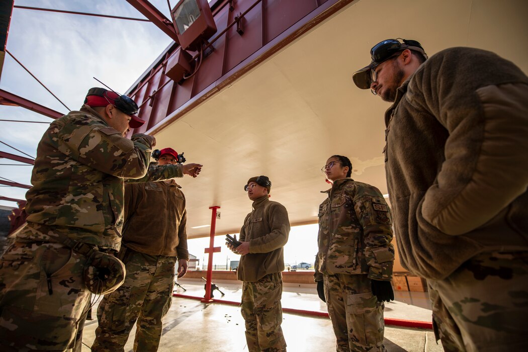 A group of five Airmen are gathered together to discuss range safety.