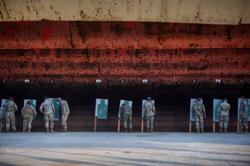 A image viewing down range from the position where shooters took thier shots from. You can see a large number of Airmen gathered around their targets reviewing how well they hit their targets.