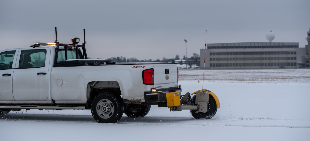 Rome Alcantara, 88th Operations Support Squadron airfield manager, drives a pickup truck with an attached runway-friction device at Wright-Patterson Air Force Base, Ohio, Jan. 23, 2023. The device is a computerized tire that measures the distance it takes to stop. That information is then uploaded to a website where pilots can see what time the test was done and if surface conditions are good. (U.S. Air Force photo by Matthew Clouse)