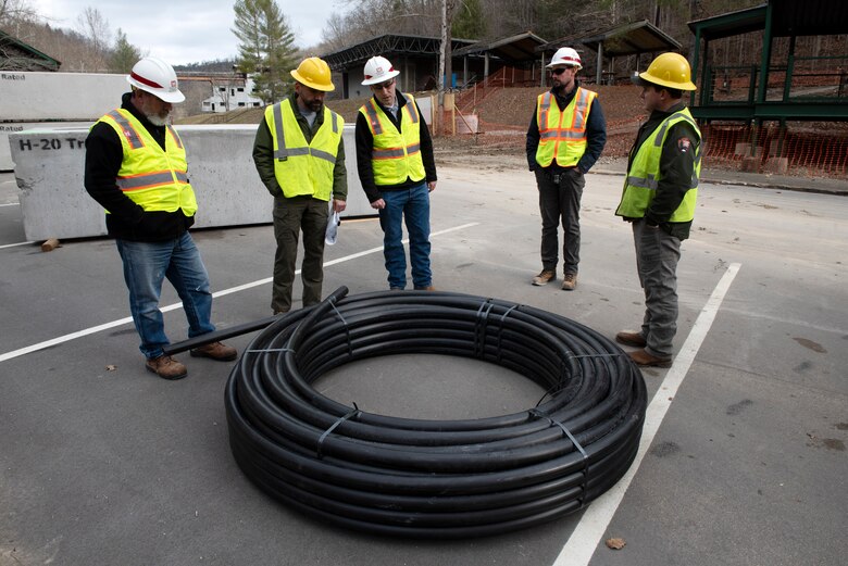 U.S. Army Corps of Engineers Nashville District and National Park Service officials look at the high-density polyethylene tubing Jan. 20, 2023, prior to its installation. Construction for a wastewater project is underway to provide a sanitary upgrade for the National Park Service Blue Heron Mine at the Big South Fork National River and Recreation Area in Stearns, Kentucky. (USACE Photo by Lee Roberts)