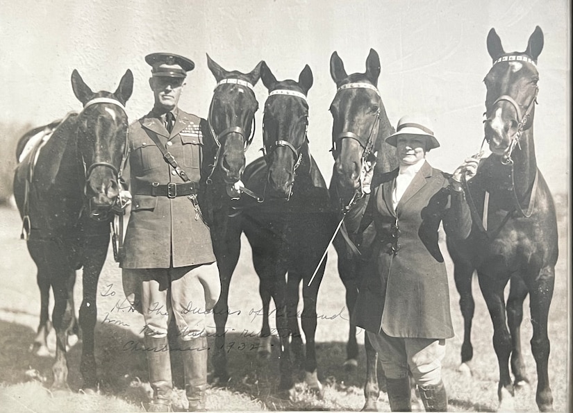 A man and woman hold the reins of five horses.