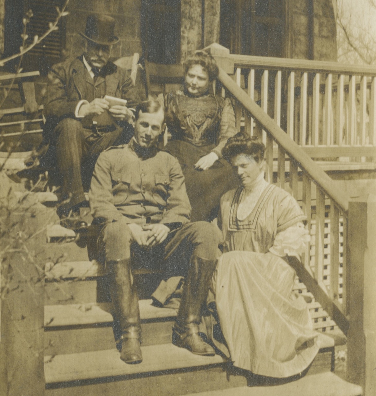 Four people sit on porch steps to pose for a photo.