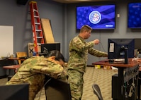 .S. Army Majs. Tania Sang and Frank Kirbyson, both assigned to Joint Task Force Civil Support, assemble their workstations in a newly-renovated joint operations center in JTF-CS headquarters on Fort Eustis, Virginia, Nov. 23, 2022.