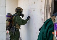 Lance Cpl. Justin Wojtyslak, a member of the hazardous materials response team assigned to the Marine Corps Chemical, Biological Incident Response Force, marks a building before entering to check for notional toxic industrial chemical contamination during Exercise Sudden Response 23 at Fort Hood, Texas Dec. 9, 2022.