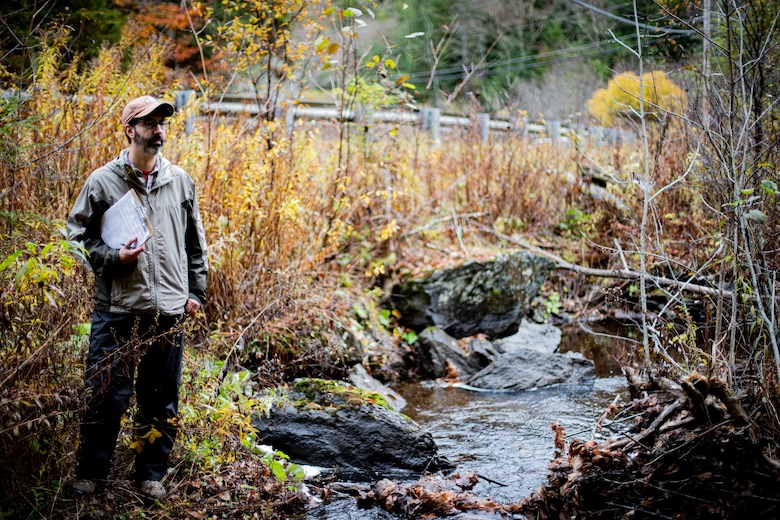 Daniel Vasconcelos, a regulator from the U.S. Army Corps of Engineers (USACE) New England District and member of the National Technical Committee for Ordinary High Watermarks (OHWM), stands along a river in Vermont while field testing an interim OHWM identification data sheet.