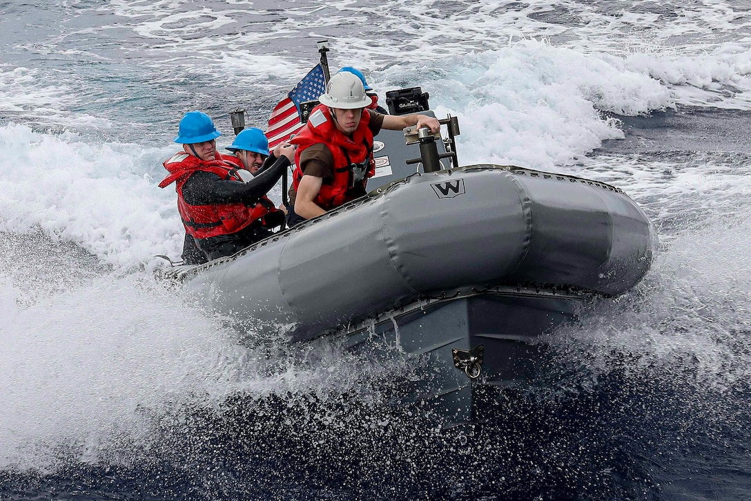 A group of sailors ride in an inflatable boat in open water.