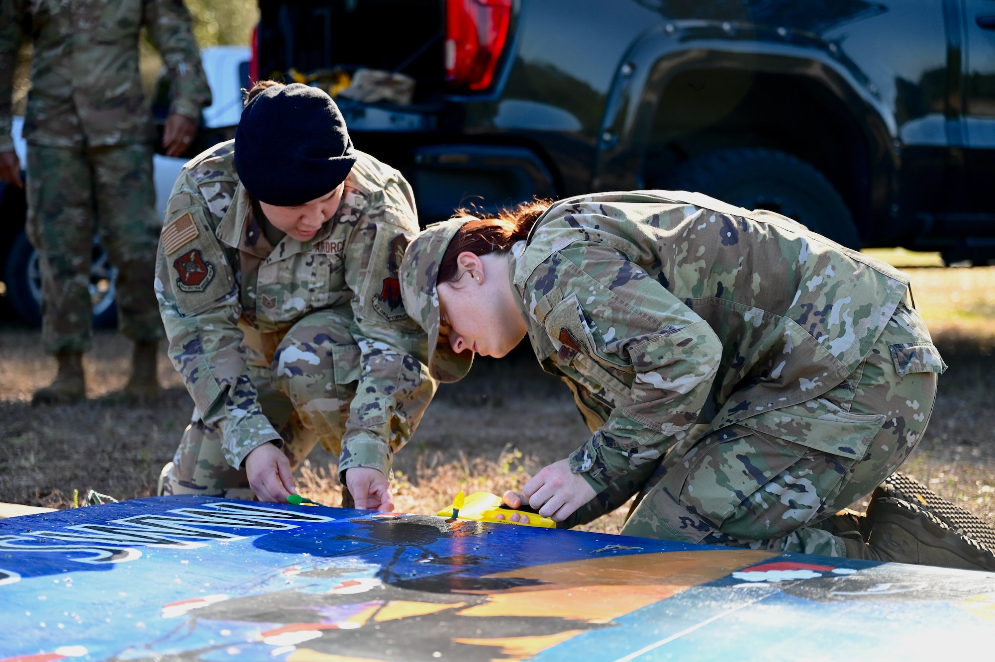 U.S. Air Force Tech. Sgt. Eddylou Potts, 350th Spectrum Warfare Wing inspector general self-assessment program manager, and U.S. Air Force Senior Airman Robbi Termentozzi, 350th SWW Program Management Office programs manager, work on connecting lights to the 350th SWW's holiday greeting card at Eglin Air Force Base, Fla., Dec. 2, 2022. This year marks the 38th Annual Holiday Greeting Card Competition where all base organizations can create a giant holiday card to be displayed on Eglin boulevard. (U.S. Air Force photo by 1st Lt. Benjamin Aronson)