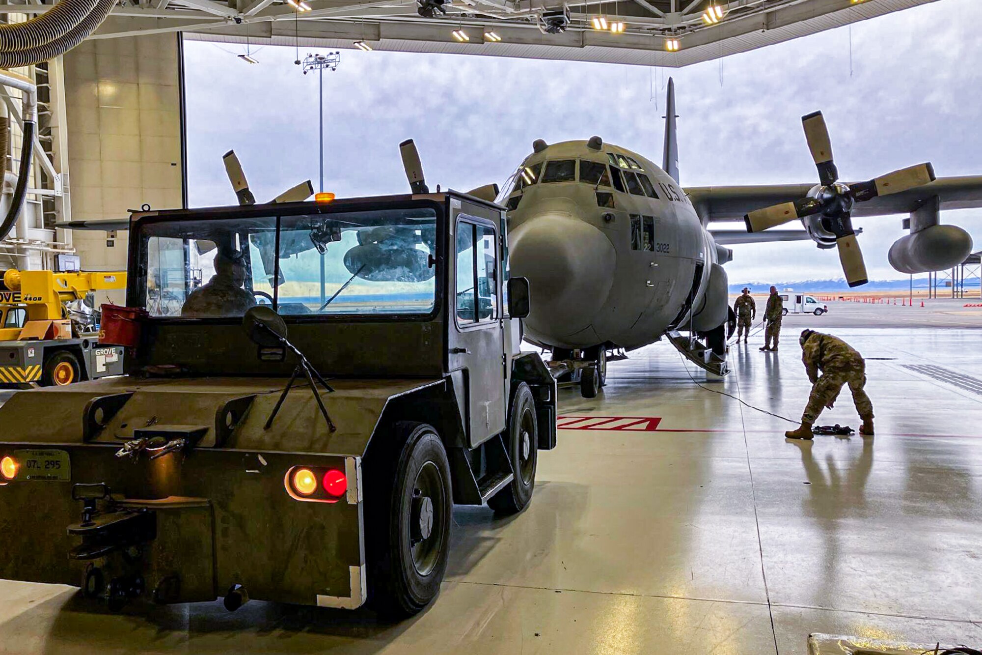 A maintenance recovery team from the 910th Airlift Wing tows a C-130H Hercules aircraft out of a hangar at Mountain Home Air Force Base, Idaho, Jan. 11, 2022.