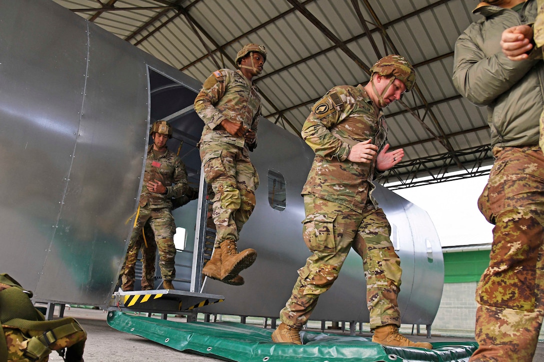 Soldiers jump out of a mock aircraft during training.