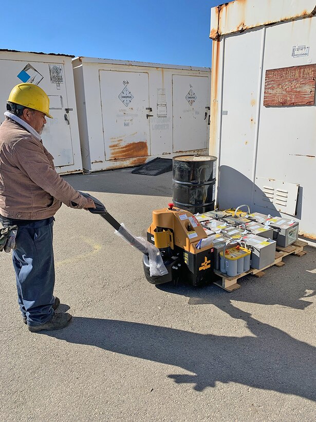 A man in a hard hat operates a pallet jack.
