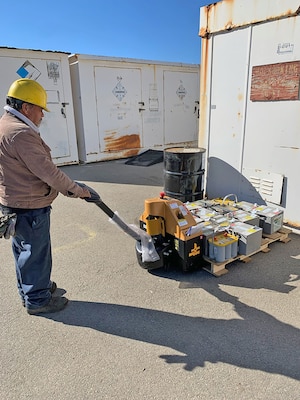 A man in a hard hat operates a pallet jack.