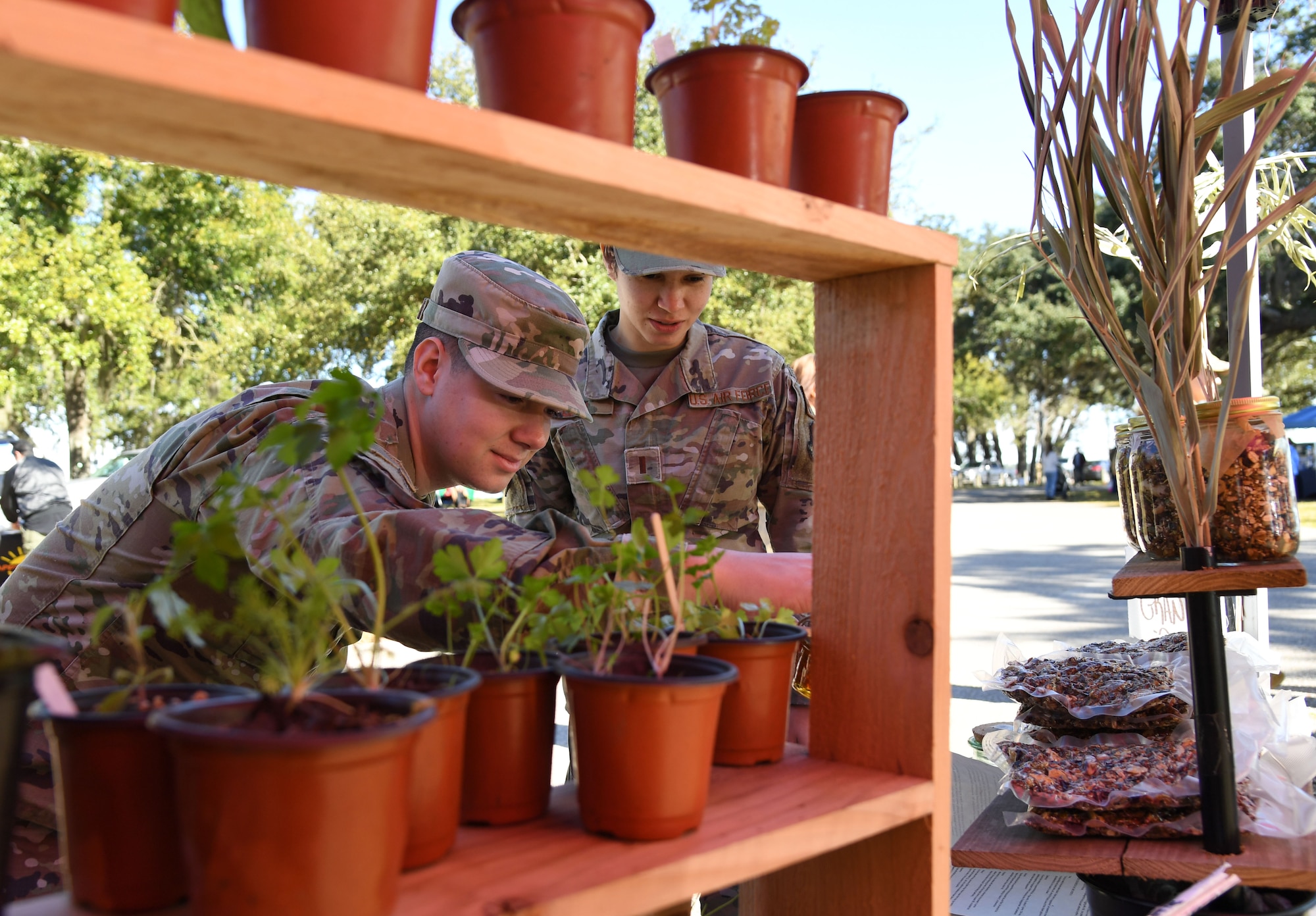 U.S. Air Force Airman 1st Class Trenten Walters, 81st Training Wing public affairs photojournalist, and 2nd Lt. Kristina Dean, 81st TRW public affairs officer, inspect planted herbs during the Farmer's Market at the marina park at Keesler Air Force Base, Mississippi, Jan. 27, 2023.