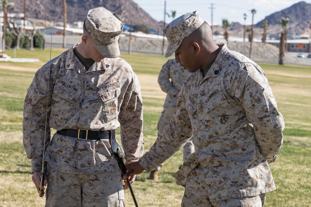 U.S. Marine Corps Staff Sgt. Vincent Walters(right) and Cpl. James Valentino, with 3d Light Armored Reconnaissance, 1st Marine Division, reviews sword manual during Corporals Course 1-23 at Marine Air Ground Combat Center, Twentynine Palms, California, Jan. 17, 2023. Corporals Course trains Marines to better lead Marines underneath them and prepare them for promotion to Sergeant. (U.S. Marine Corps Photo by Lance Cpl. Anna Higman)