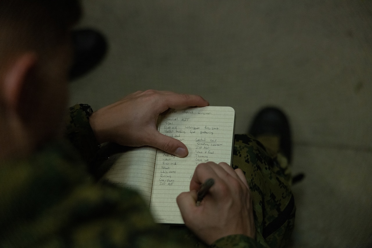 A Marine takes notes in a journal.