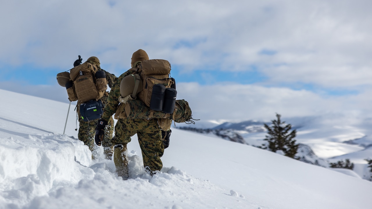 Marines hike a snowy mountain.