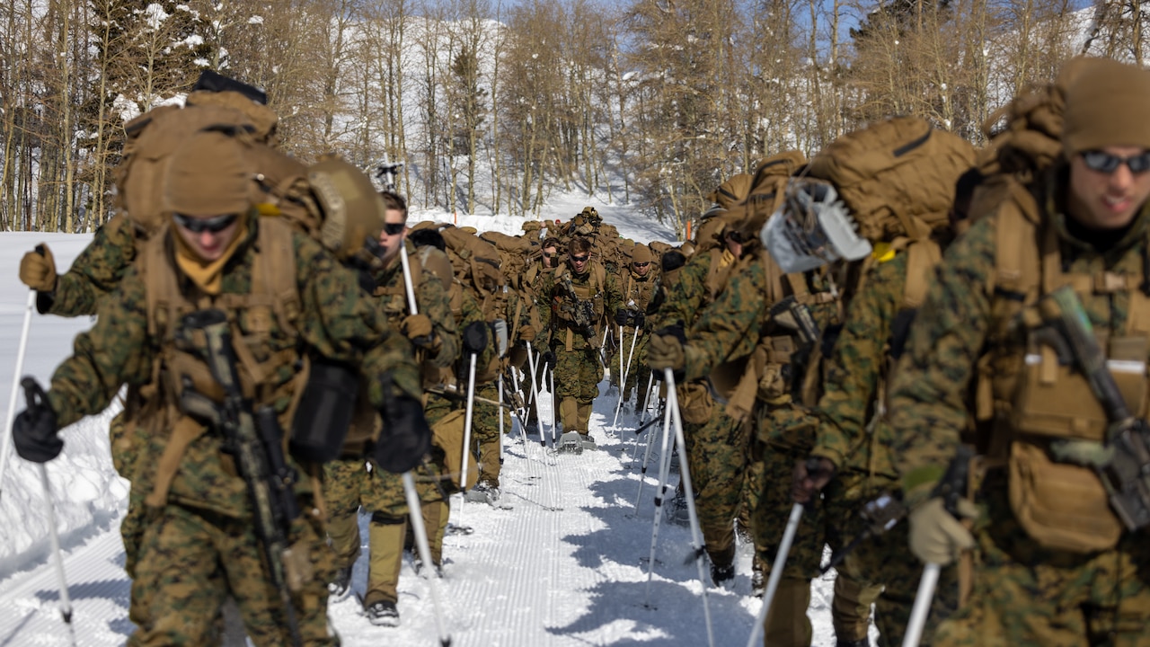 A group of Marines hike in the snow.