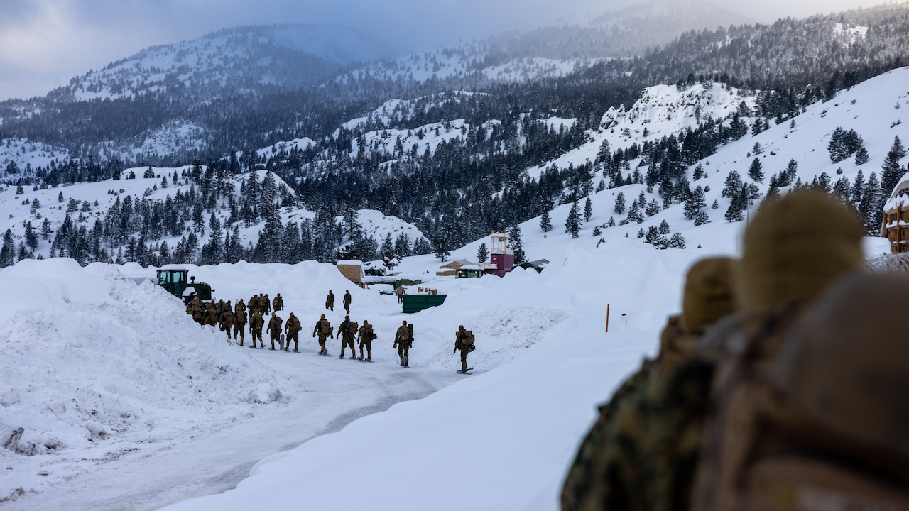 Marines hike on snowy mountains.