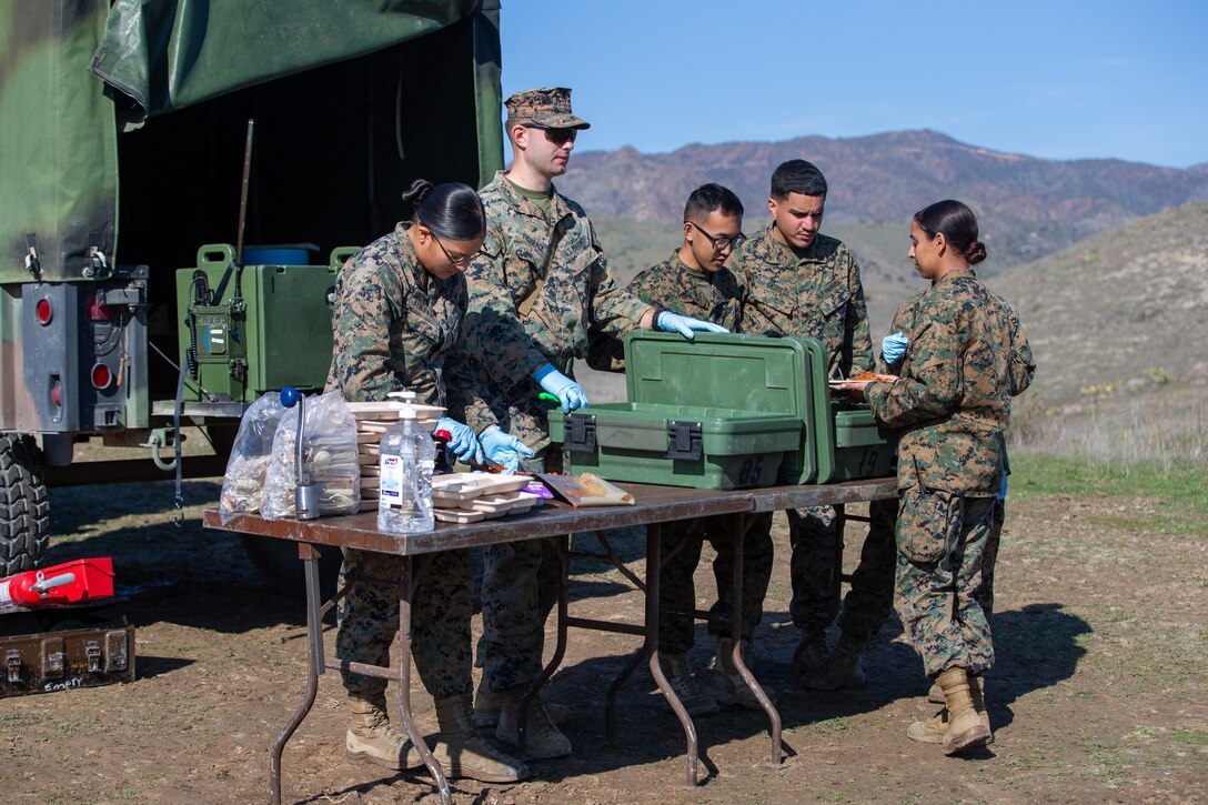 U.S. Marines with I Marine Expeditionary Force Support Battalion, I MEF Information Group, serve food during a Combat Service Support Company field exercise at Marine Corps Base Camp Pendleton, California, Dec. 14, 2022. CSSC conducted the field exercise to meet operational and training objectives to enhance deployment capabilities and unit readiness. (U.S. Marine Corps photo by Sgt. Alize Sotelo)