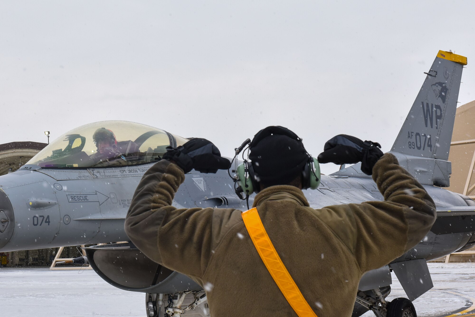 Airman 1st Class Zakkee Conwell, 80th Fighter Generation Squadron crew chief, poses with the ‘Crush ‘em’ hand gesture as U.S. Air Force Lt. Gen. Scott “Rolls” Pleus, 7th Air Force commander prepares to depart in an F-16 Fighting Falcon, at Kunsan Air Base, Republic of Korea, Jan. 26, 2023. The 80th Fighter Generation Squadron ‘Juvats’ are also known as the Headhunters. (U.S. Air Force photo by Tech. Sgt. Timothy Dischinat)