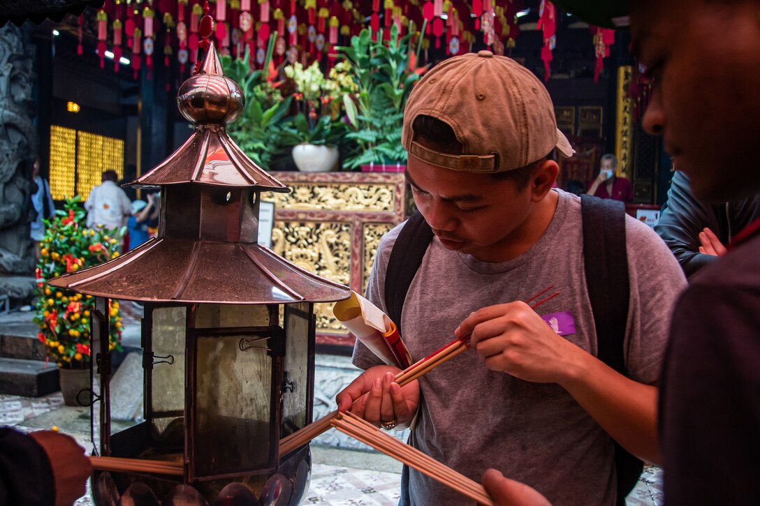 A sailor in civilian clothes puts incense  in a lantern.