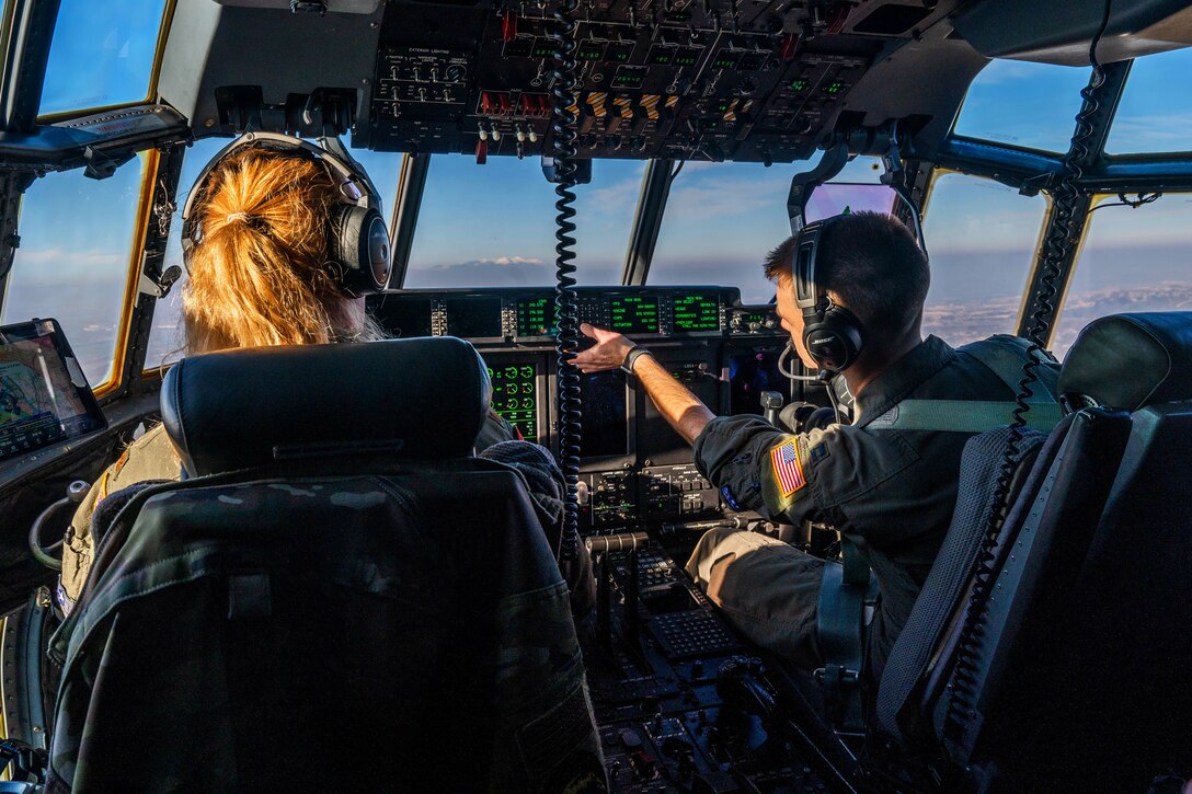 Two pilots sit in the cockpit of an airplane while airborne.