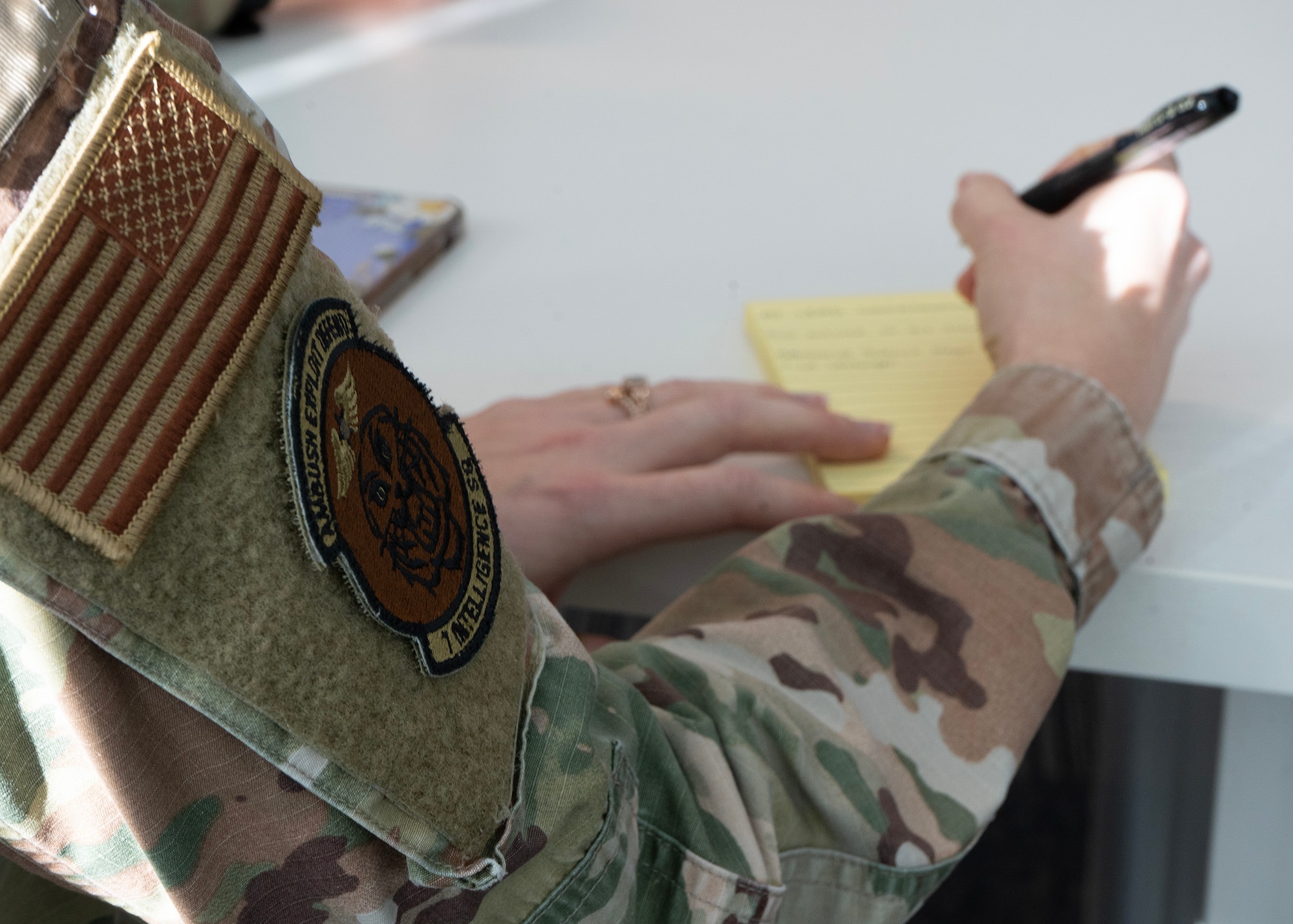 An Airman assigned to the 7th Intelligence Squadron takes notes during a commissioning opportunity Jan. 26, 2023, at Fort George G. Meade, Maryland. The 659th Intelligence, Surveillance and Reconnaissance Group hosted the event, which informed Airmen about how to commission through the U.S. Air Force Academy. The U.S. Air Force offers enlisted members various paths to commission as an officer through programs such as the Academy, Leader Encouraging Airmen Development, and Officer Training School. (U.S. Air Force photo by Staff Sgt. Kevin Iinuma)