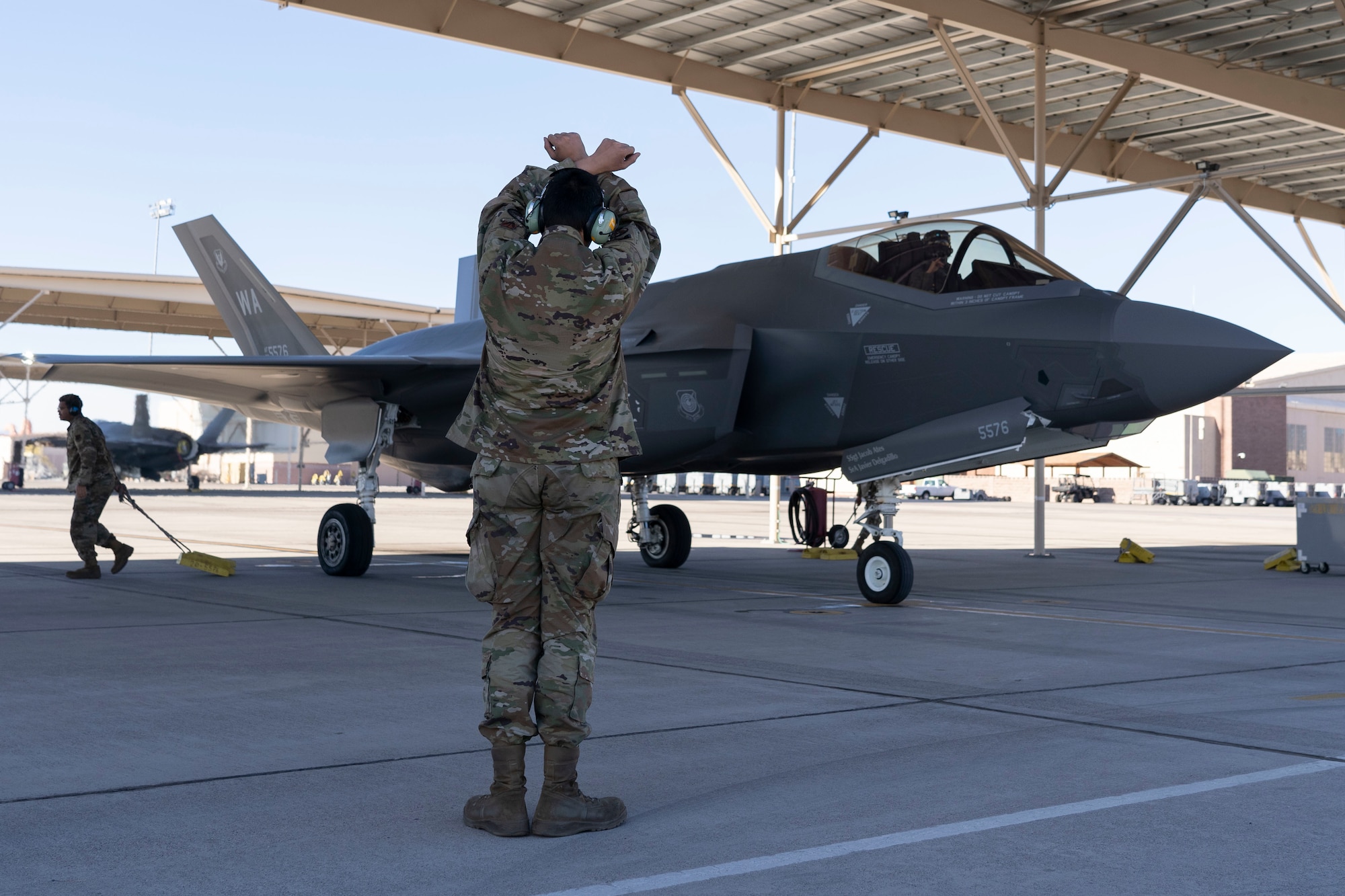 Senior Airman Patrick Bellar, a Lightning Air Maintenance Unit Crew Chief, marshals an F-35A Lightning II piloted by Brig. Gen. Michael Rawls, Air Force Operational Test and Evaluation Center commander prior to taxiing at Nellis Air Force Base, Nevada, Jan. 12, 2023. Having the AFOTEC commander flying with the 65th Aggressors is a unique and opportunistic relationship where he can directly see the effects of his organization on warfighter training. (U.S. Air Force Photo by Airman First Class Trevor Bell)