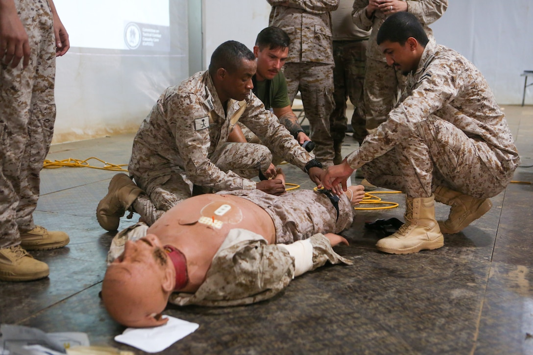 U.S. Navy Hospital Corpsman 2nd Class Austin Santistevan with Combat Logistics Regiment 1, 1st Marine Logistics Group, and Saudi Armed Forces members put a tourniquet on a simulated causality during a combat life saver course during exercise Native Fury 22 at the Logistics Support Area, Kingdom of Saudi Arabia, Aug. 9, 2022. Native Fury 22 is a biennial exercise focused on the demonstration of the rapid offload and integration of a Maritime Prepositioned Force in the U.S. Central Command area of responsibility in support of regional security, crisis response, and contingency operations. (U.S. Marine Corps photo by Sgt. Alize Sotelo)