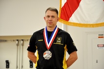 Man in competition uniform standing with medal around neck.