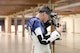 Man in shooting uniform standing with air rifle.