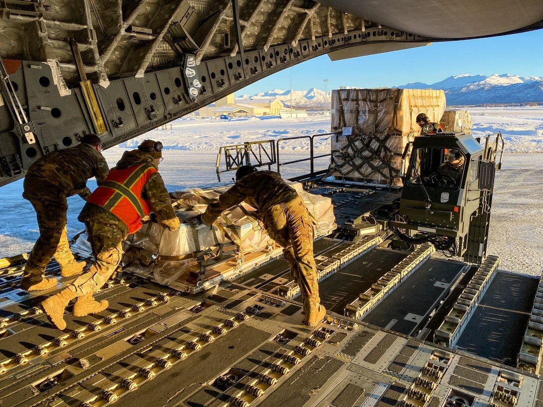 A photo of Airmen pushing cargo off of an aircraft.