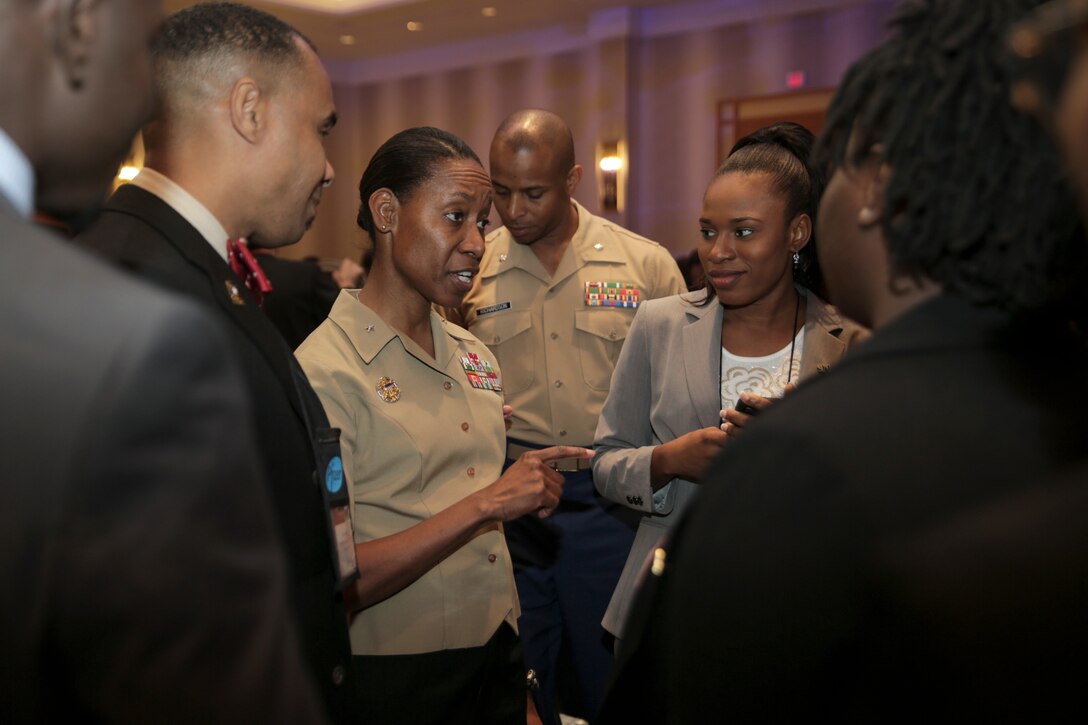 A Marine talks to civilians standing in a room.