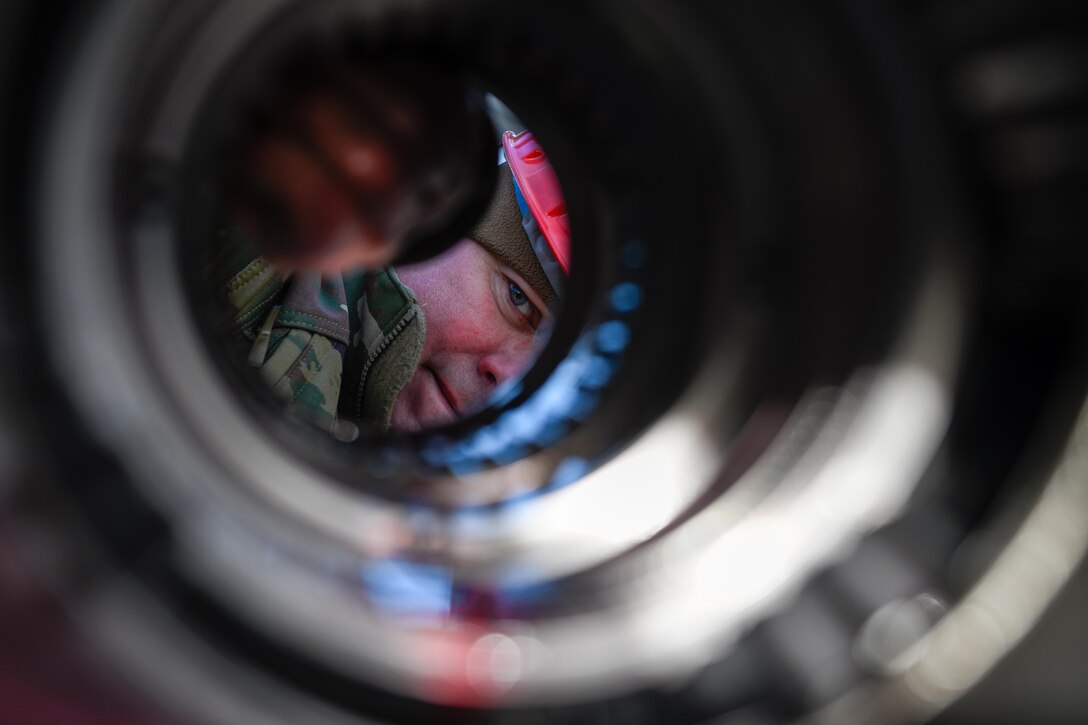 An airman’s face is shown looking down a cylinder.